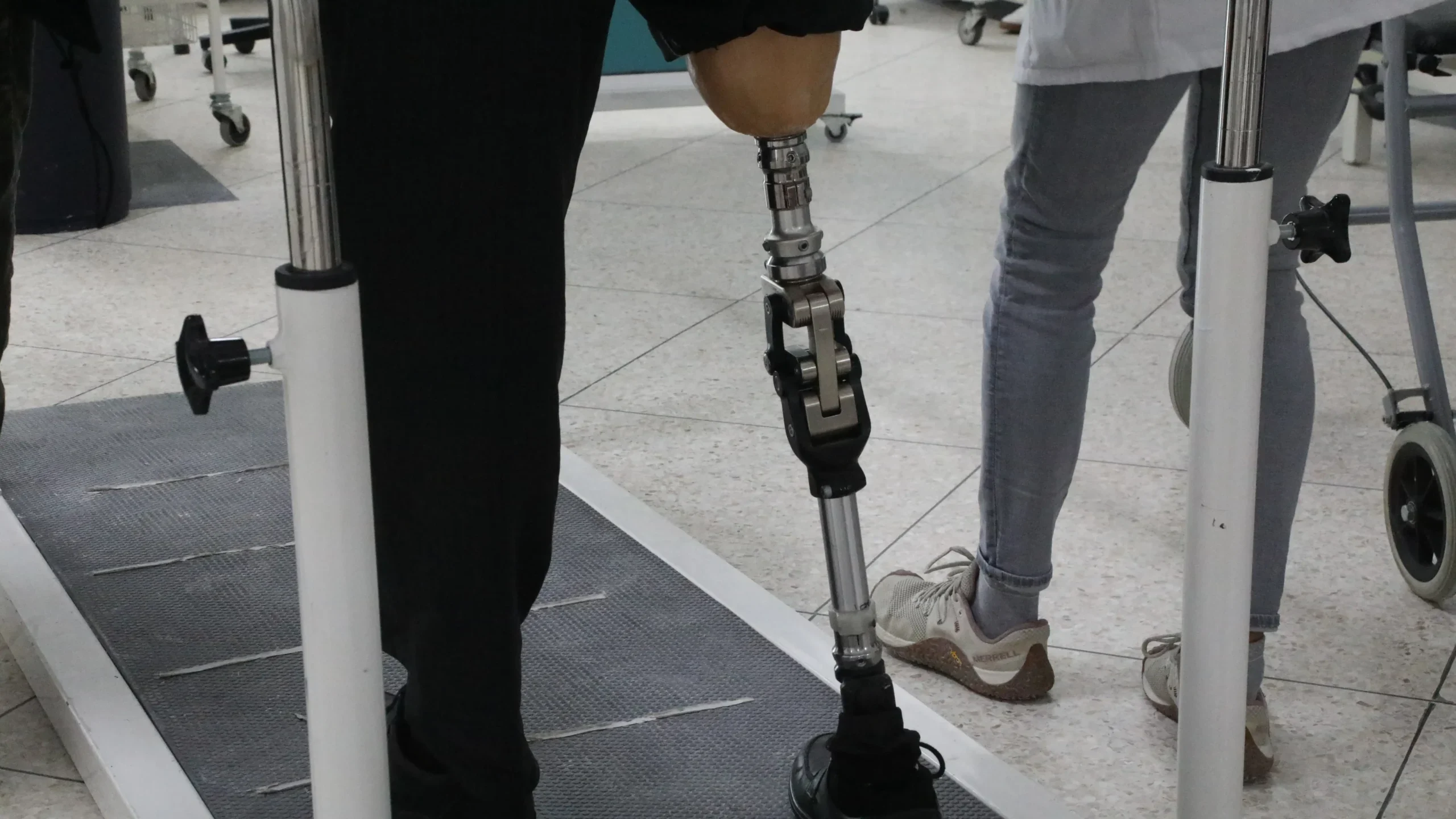Gros plan sur une prothèse de jambe lors d’un essai de marche entre les barres parallèles.